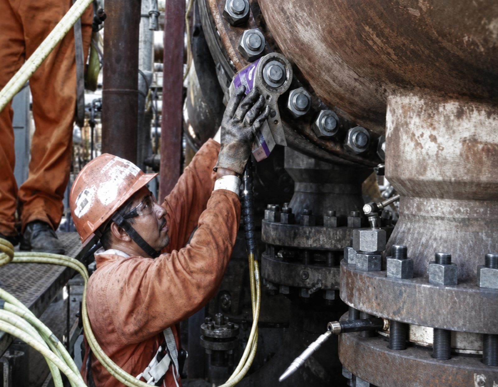 Worker in protective gear working on industrial equipment.