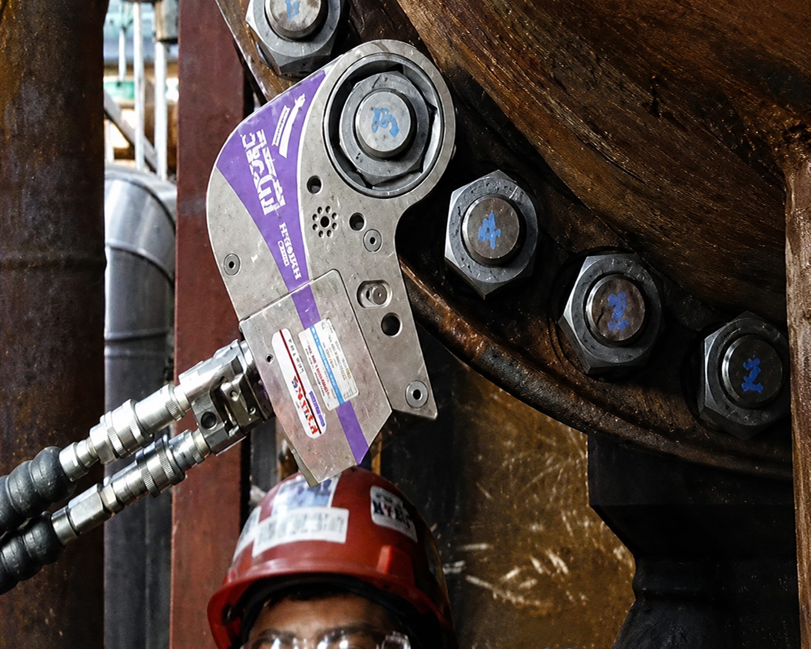 Worker using a hydraulic torque tool on a large flange.