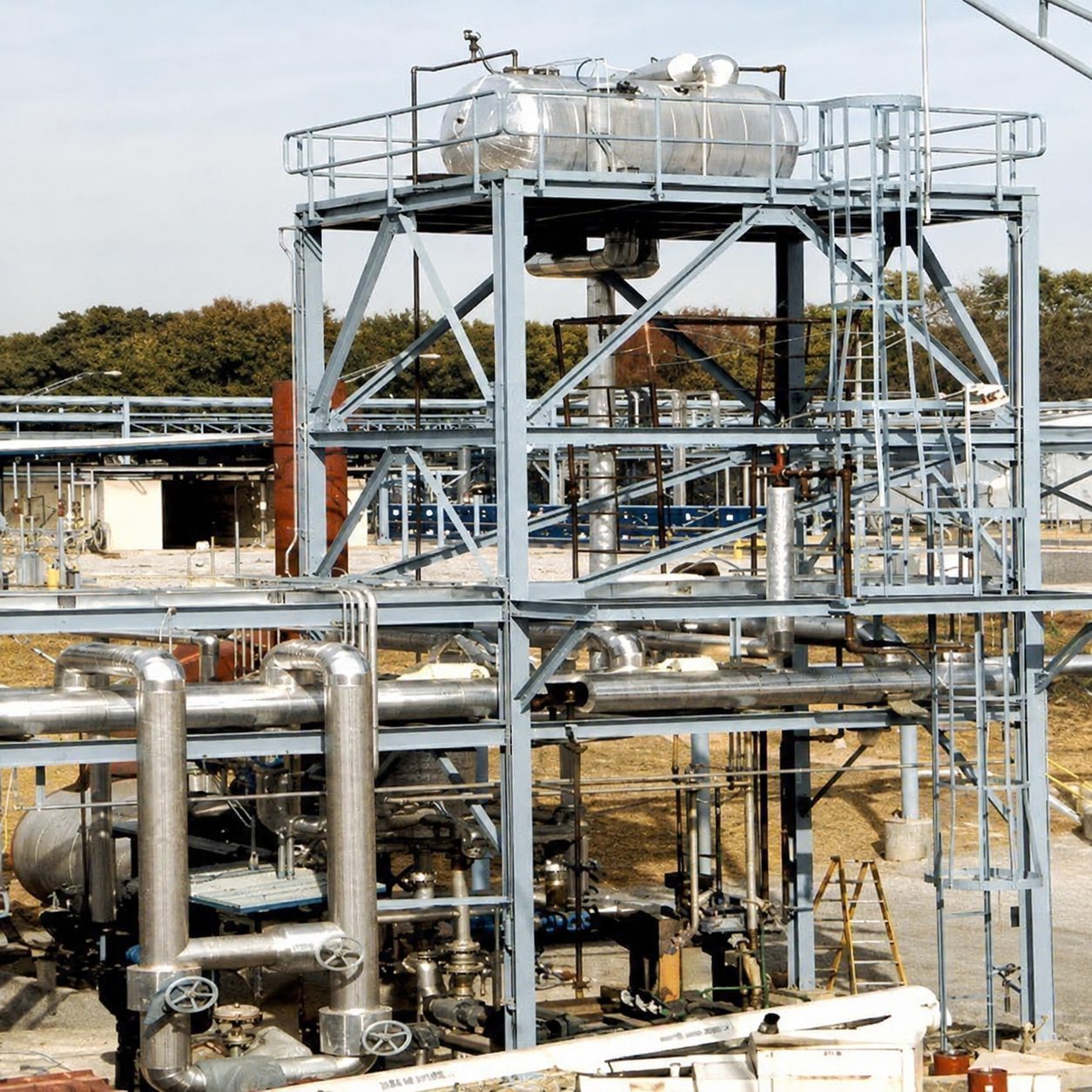 Industrial structure with metal piping and a tank on a platform.